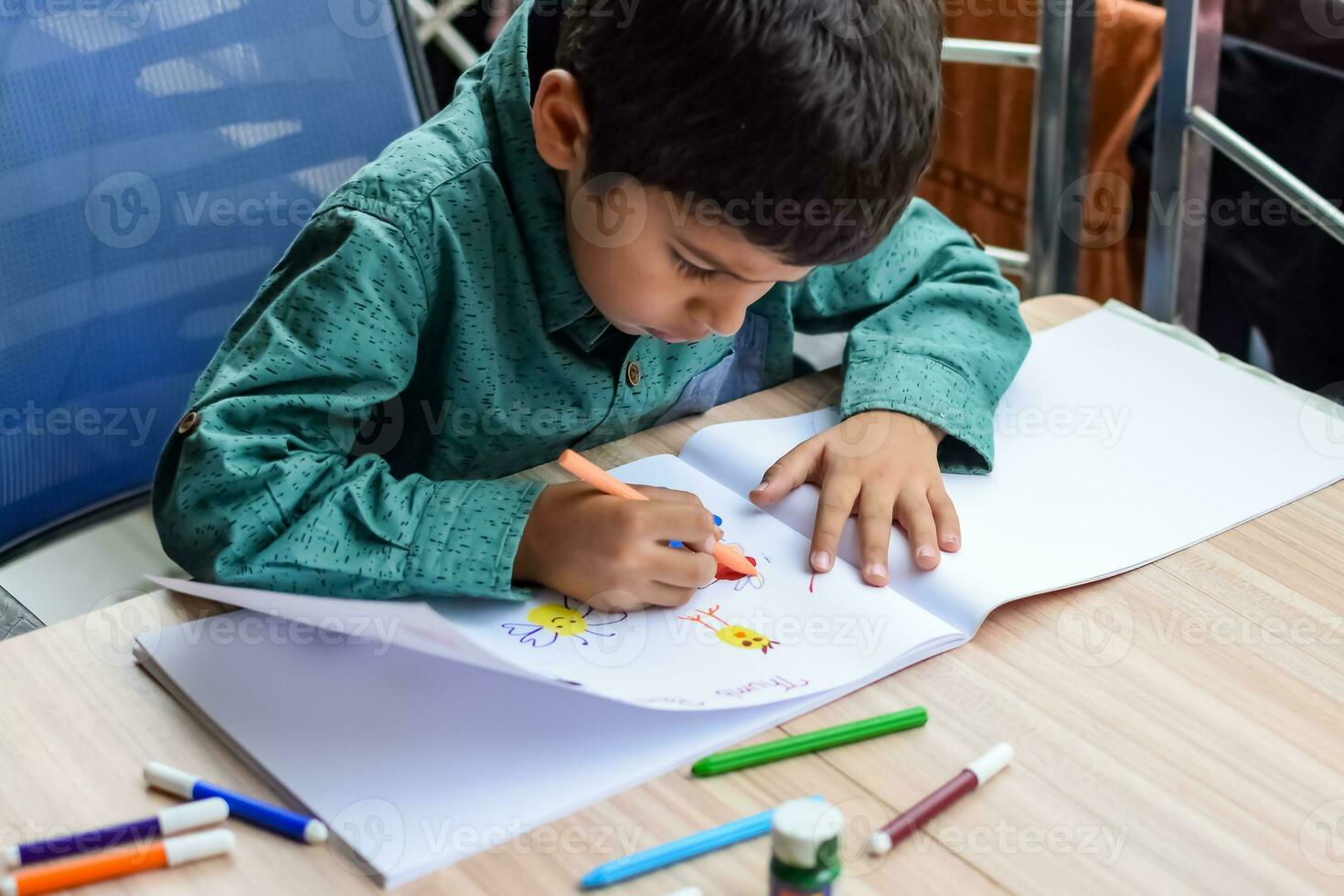 intelligent Indien peu garçon effectuer pouce La peinture avec différent coloré l'eau Couleur trousse pendant le été les vacances, mignonne Indien enfant Faire coloré pouce La peinture dessin sur en bois table photo