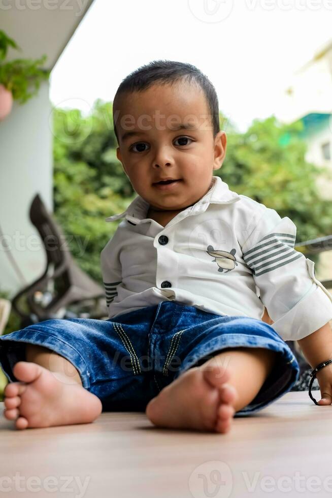 bébé garçon à Accueil balcon. brillant portrait de content enfant séance sur le tableau. peu 1 année vieux garçon pendant le journée lumière à maison balcon. photo