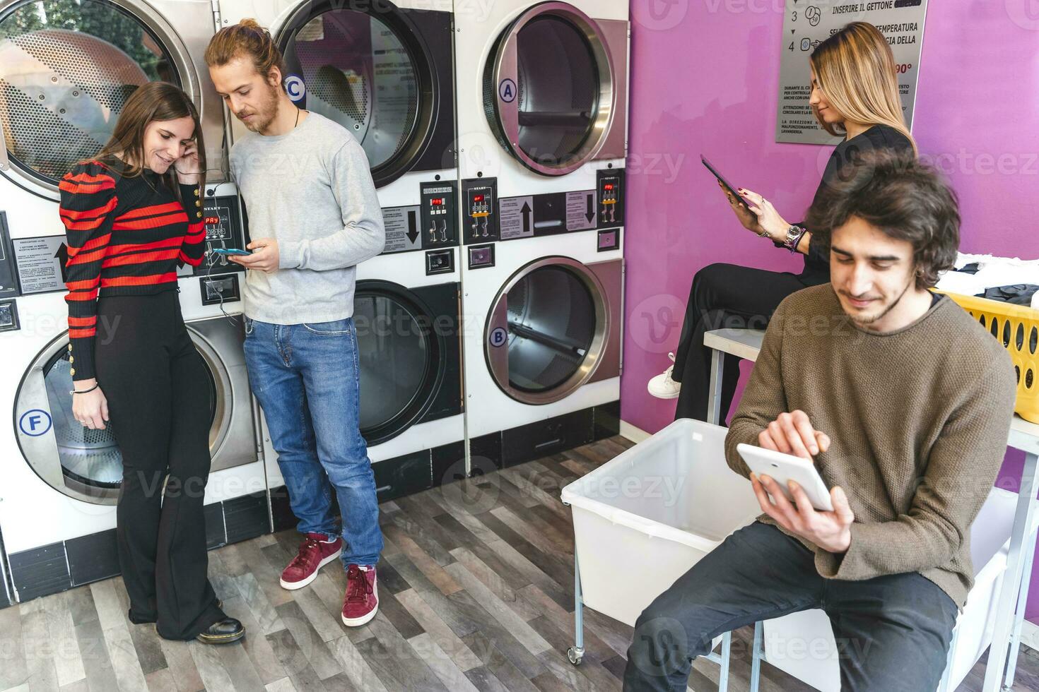 groupe de intoxiqué copains sont en jouant avec comprimés et les smartphones dans une Publique blanchisserie photo