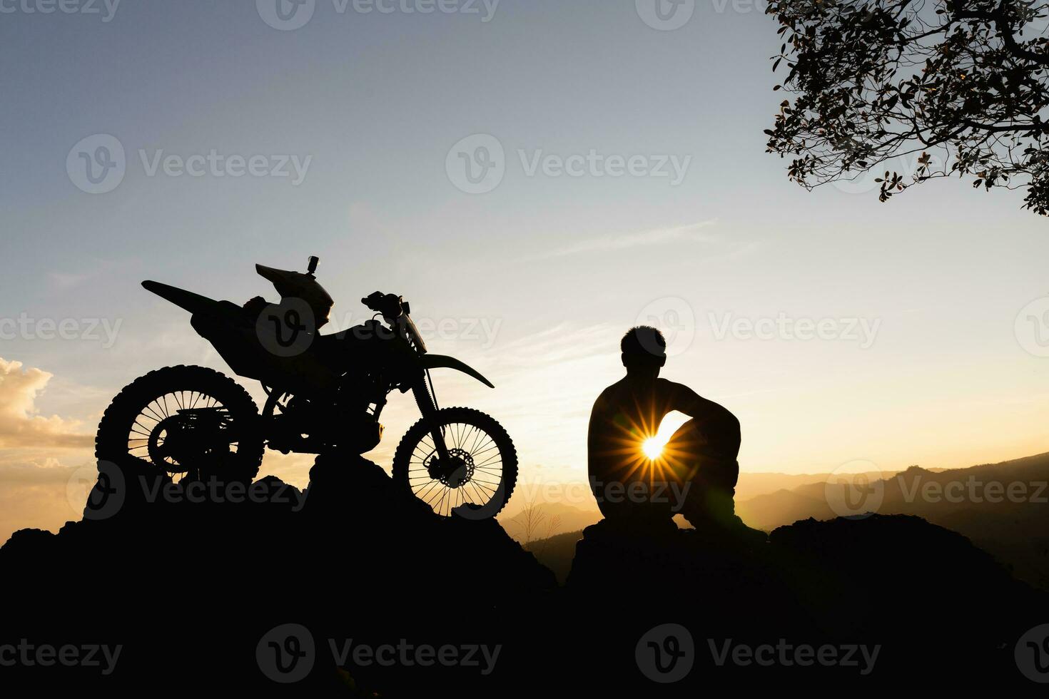 homme avec motocross bicyclette contre magnifique lumières, silhouette de une homme avec motocross moto sur Haut de Roche haute Montagne à magnifique coucher de soleil, enduro moto Voyage concept. photo