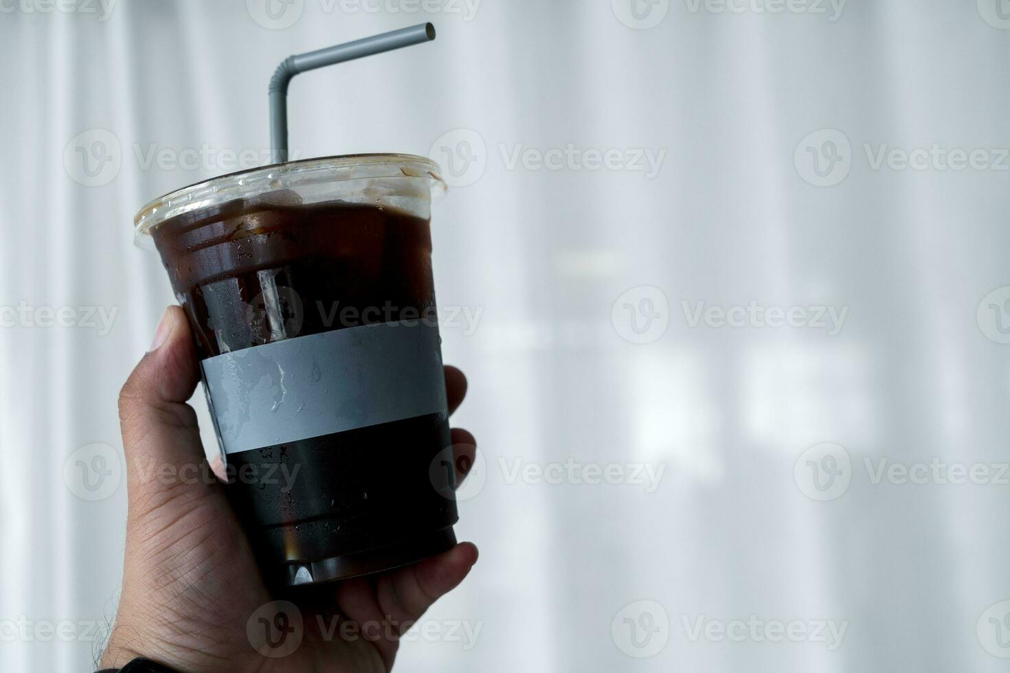 main en portant une verre de glacé café, americano dans le après midi temps photo