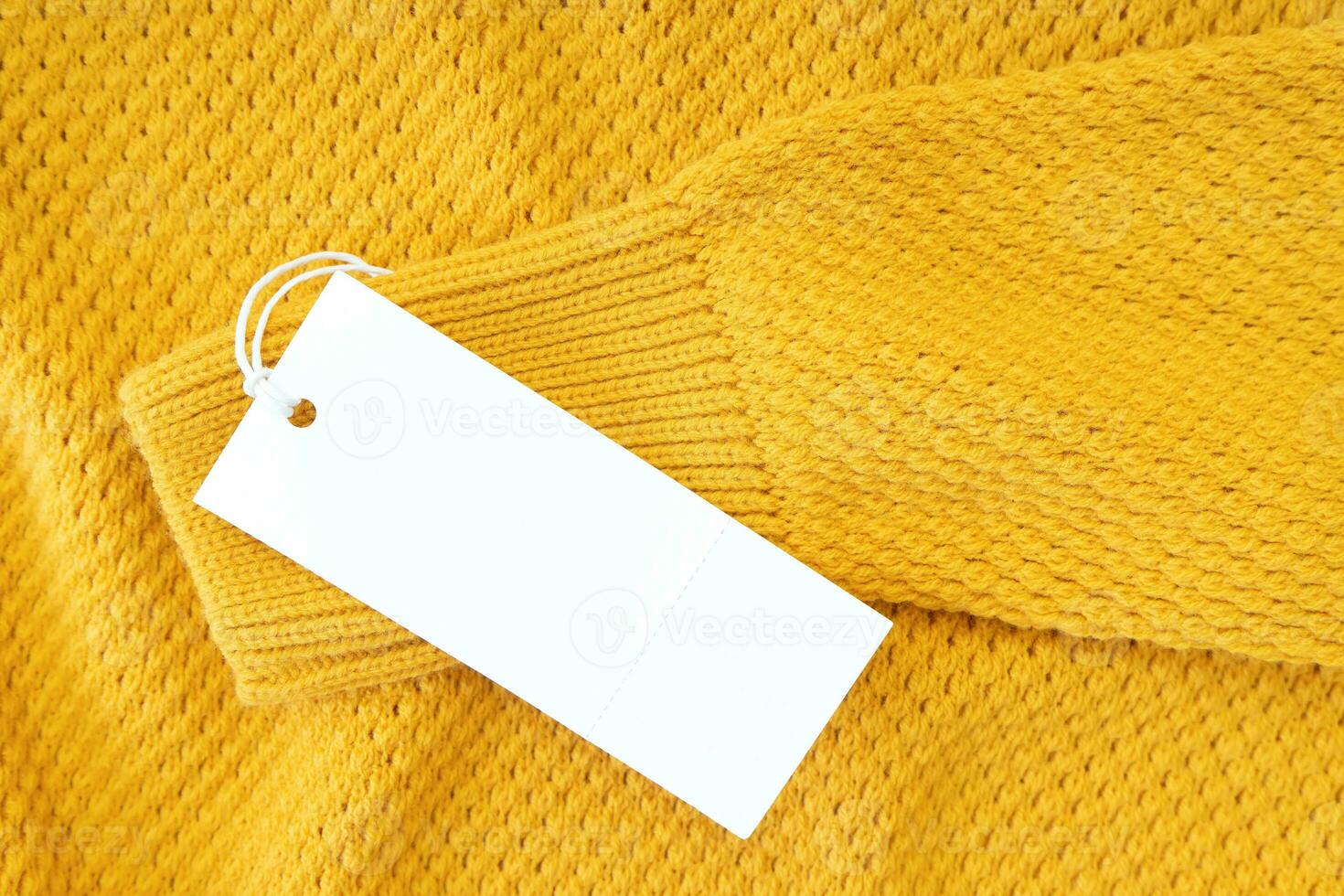 Étiquette de vêtements rectangulaire blanc blanc sur pull tricoté jaune isolé sur fond blanc photo
