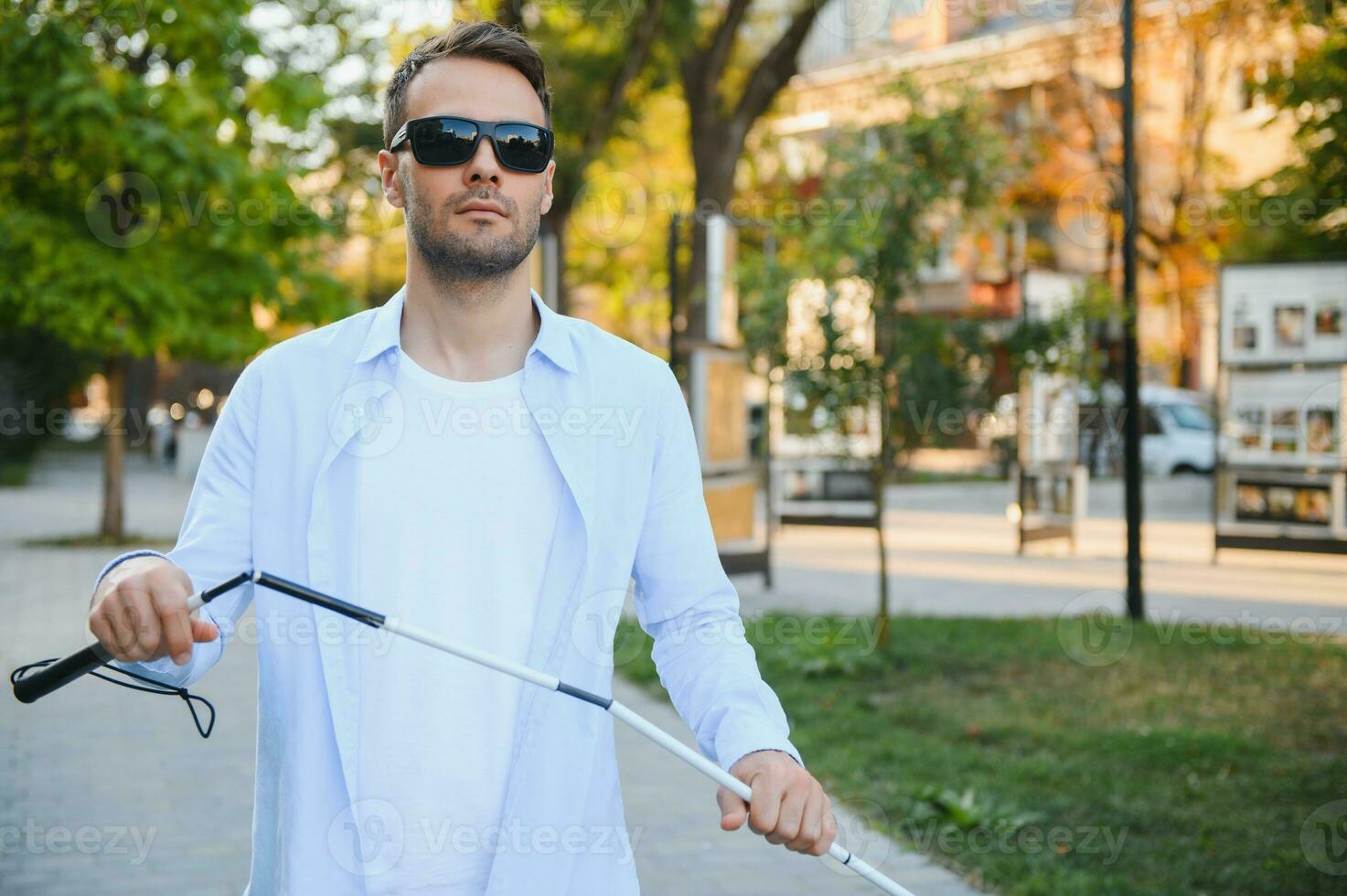 Jeune Beau aveugle homme en marchant avec bâton dans ville photo
