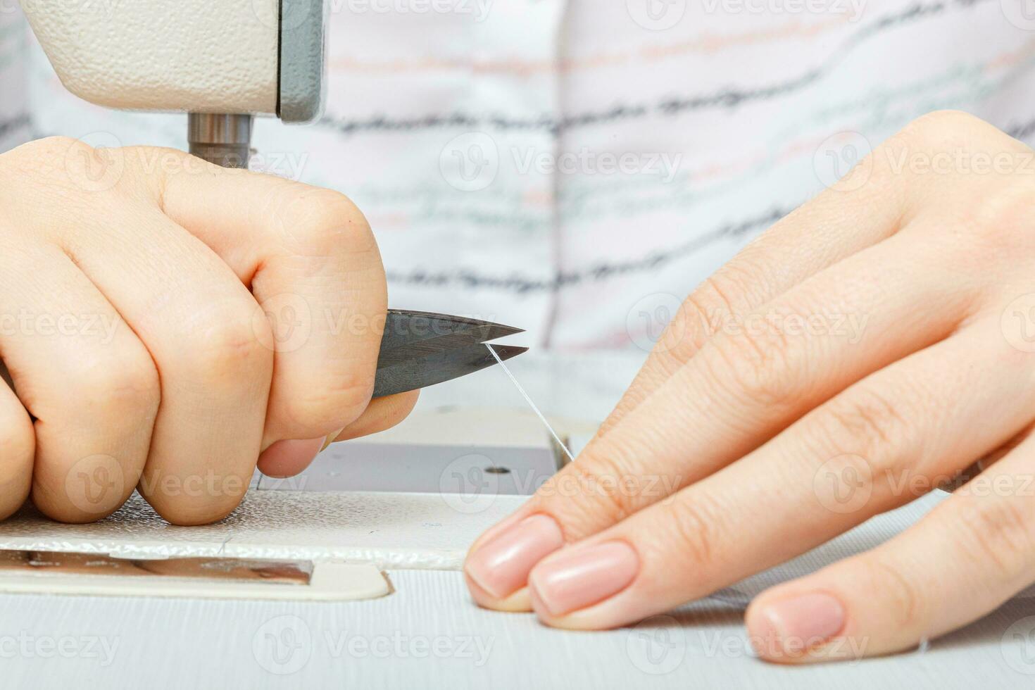 femelle mains de une Maître tailleur coupes une fil avec les ciseaux photo