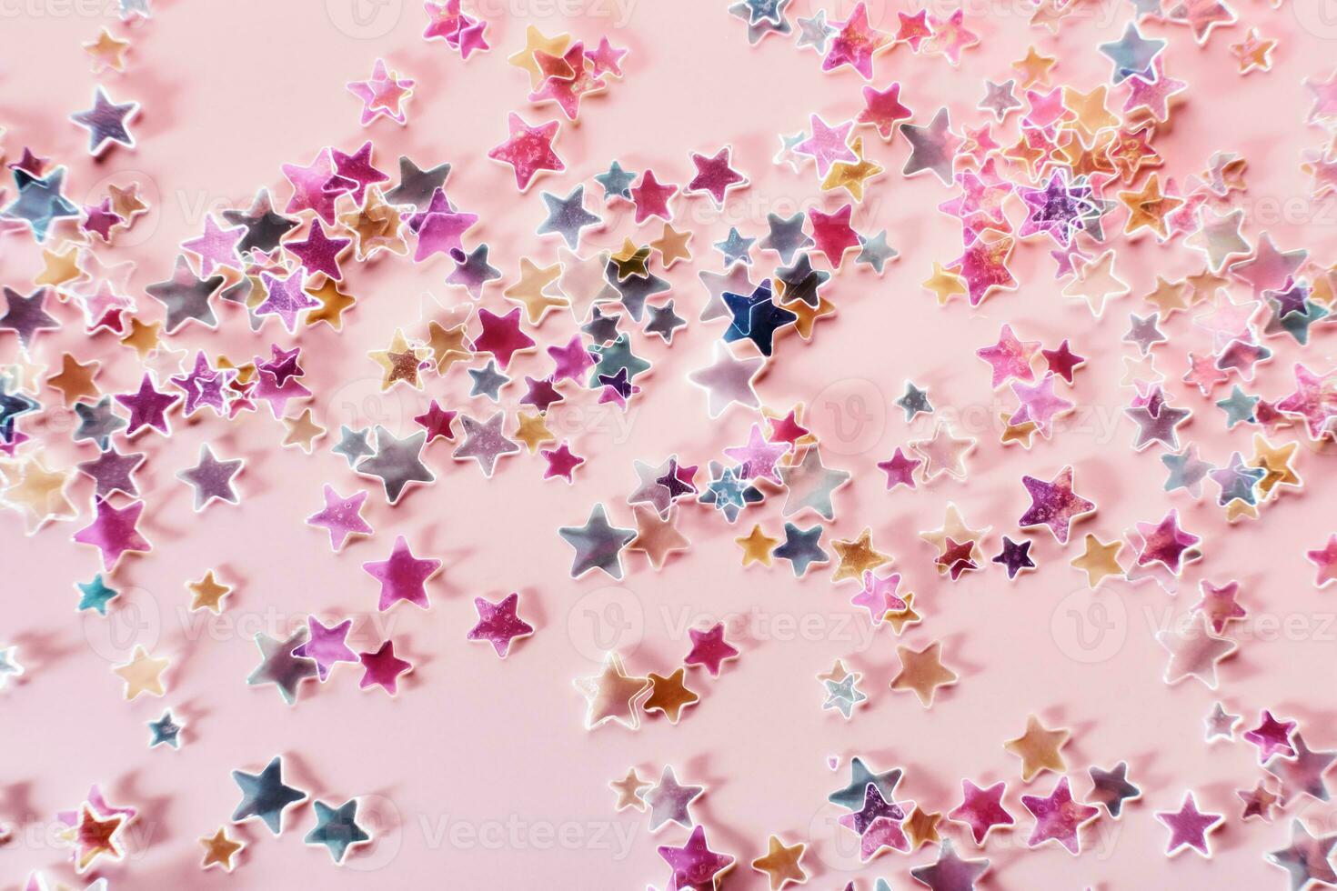 multicolore holographique étoiles briller confettis sur rose Contexte. de fête toile de fond, sélectif concentrer photo