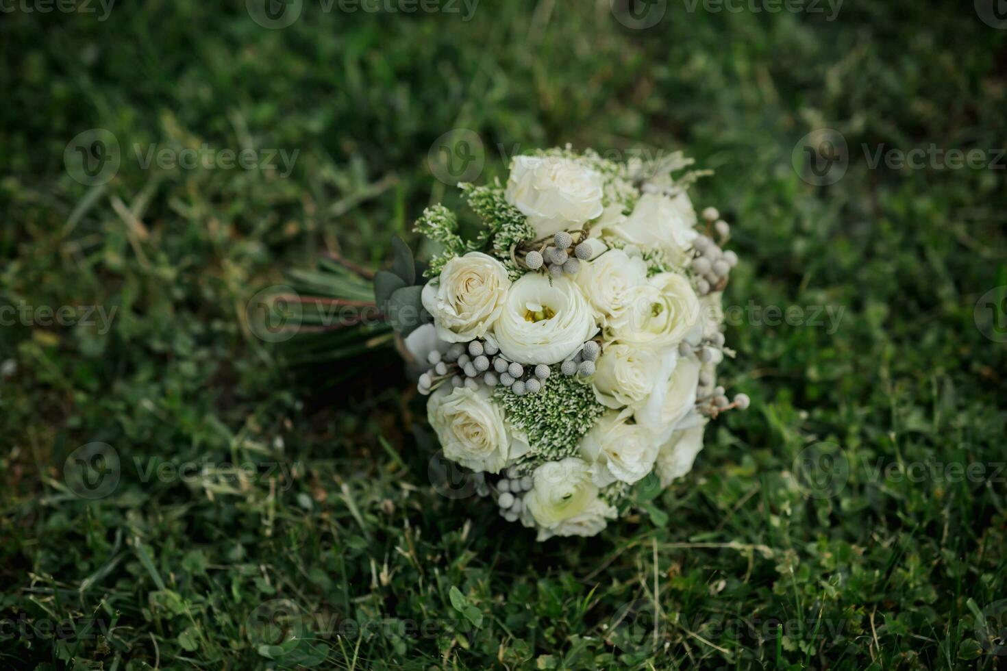 une bouquet de blanc des roses et verdure, lié avec une ruban, mensonges sur vert herbe. un incroyable mariage bouquet. blanc des roses. beauté est dans le détails photo