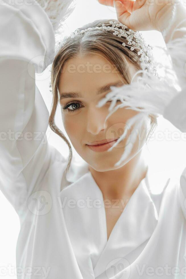 Matin de la mariée avant le mariage. magnifique Jeune femme avec longue voile dans une blanc peignoir. Naturel beauté et professionnel maquillage.fille dans blanc dentelle boudoir robe. photo