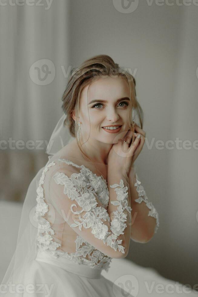 préparation pour le mariage. magnifique Jeune la mariée dans blanc mariage robe à l'intérieur. luxe modèle à la recherche en dehors fenêtre à Accueil dans studio pièce avec gros la fenêtre. le fille spectacles photo