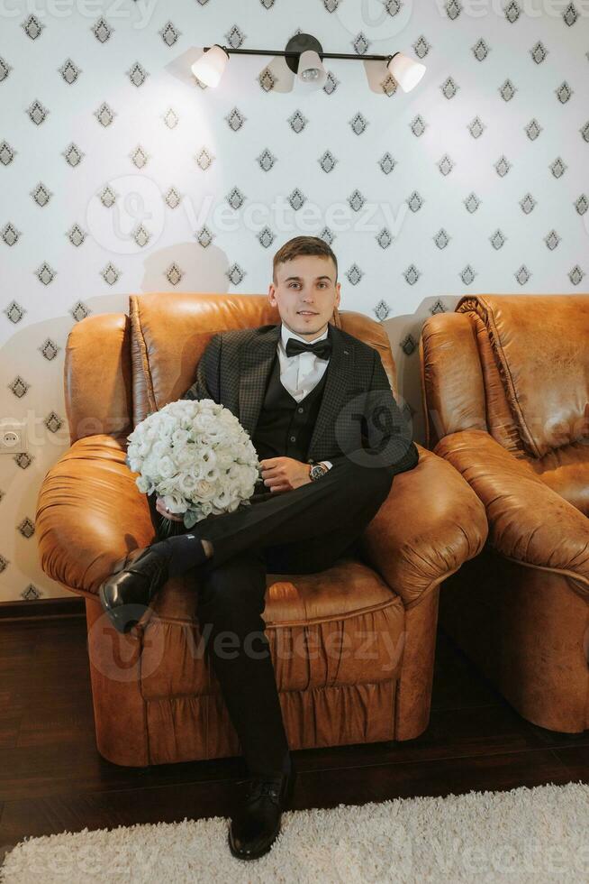 jeune marié avec une bouquet de fleurs dans une pièce avec une magnifique intérieur. le jeune marié est à la recherche à le caméra photo