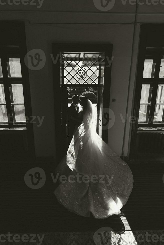 le la mariée et jeune marié supporter dans le ruelle dans le lumière de le réglage Soleil avec ombres. noir et blanc photo