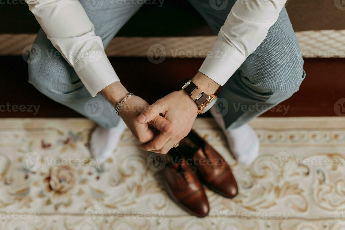 vue de au-dessus de. détails. photo de une homme mains suivant à élégant rouge Pour des hommes chaussures. une élégant montre. Pour des hommes style. mode. affaires