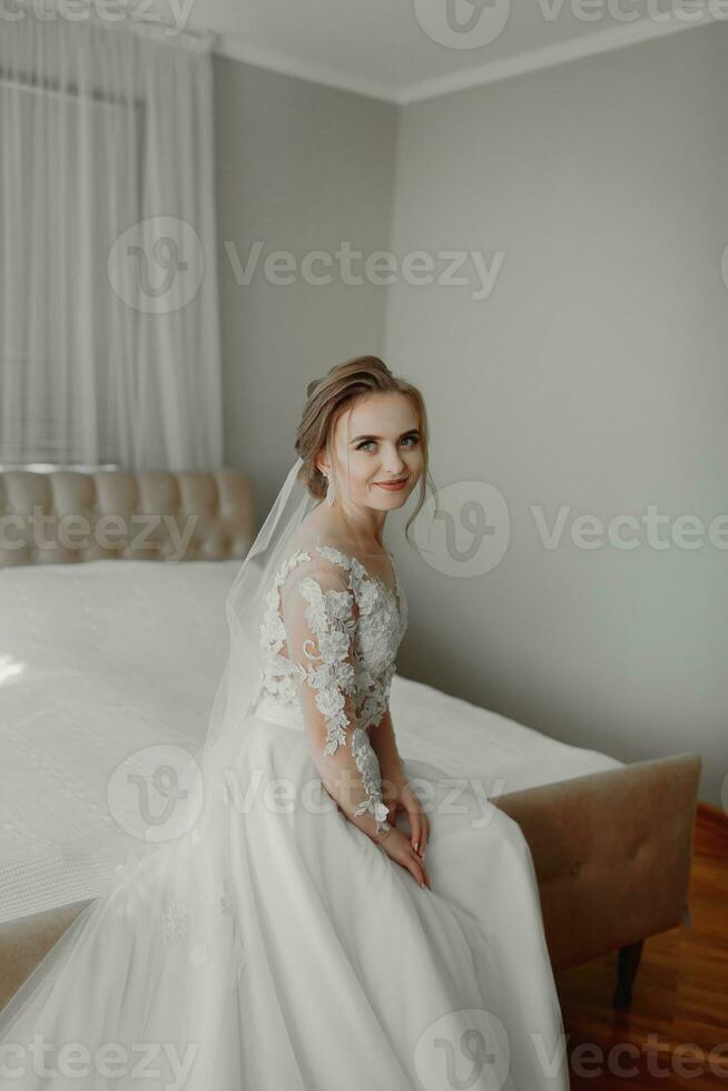 préparation pour le mariage. magnifique Jeune la mariée dans blanc mariage robe à l'intérieur. luxe modèle à la recherche en dehors fenêtre à Accueil dans studio pièce avec gros la fenêtre. le fille spectacles photo