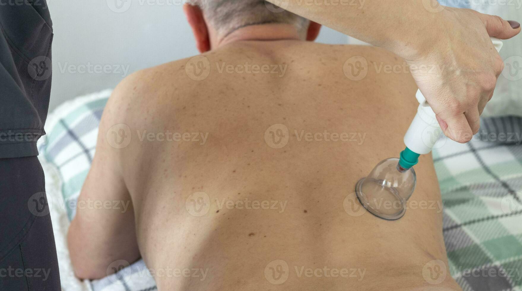 coup de le femelle médecin dans uniforme contre le blanc mur examiner milieu âge Masculin patient, performant ventouses thérapie. soins de santé photo