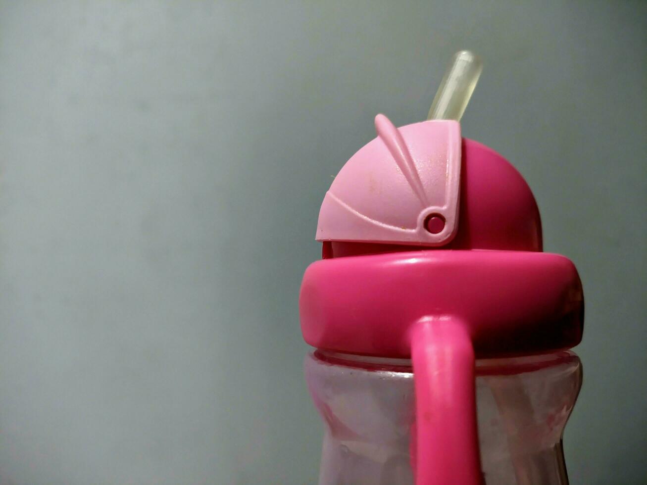 une rose enfants en buvant bouteille avec une paille à le fin photo