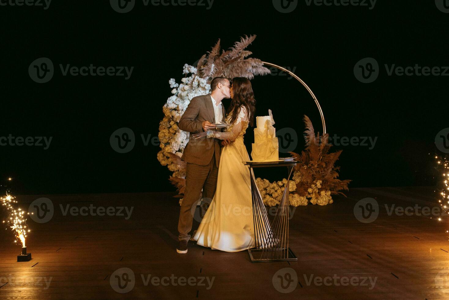 les jeunes mariés coupent et goûtent joyeusement le gâteau de mariage photo