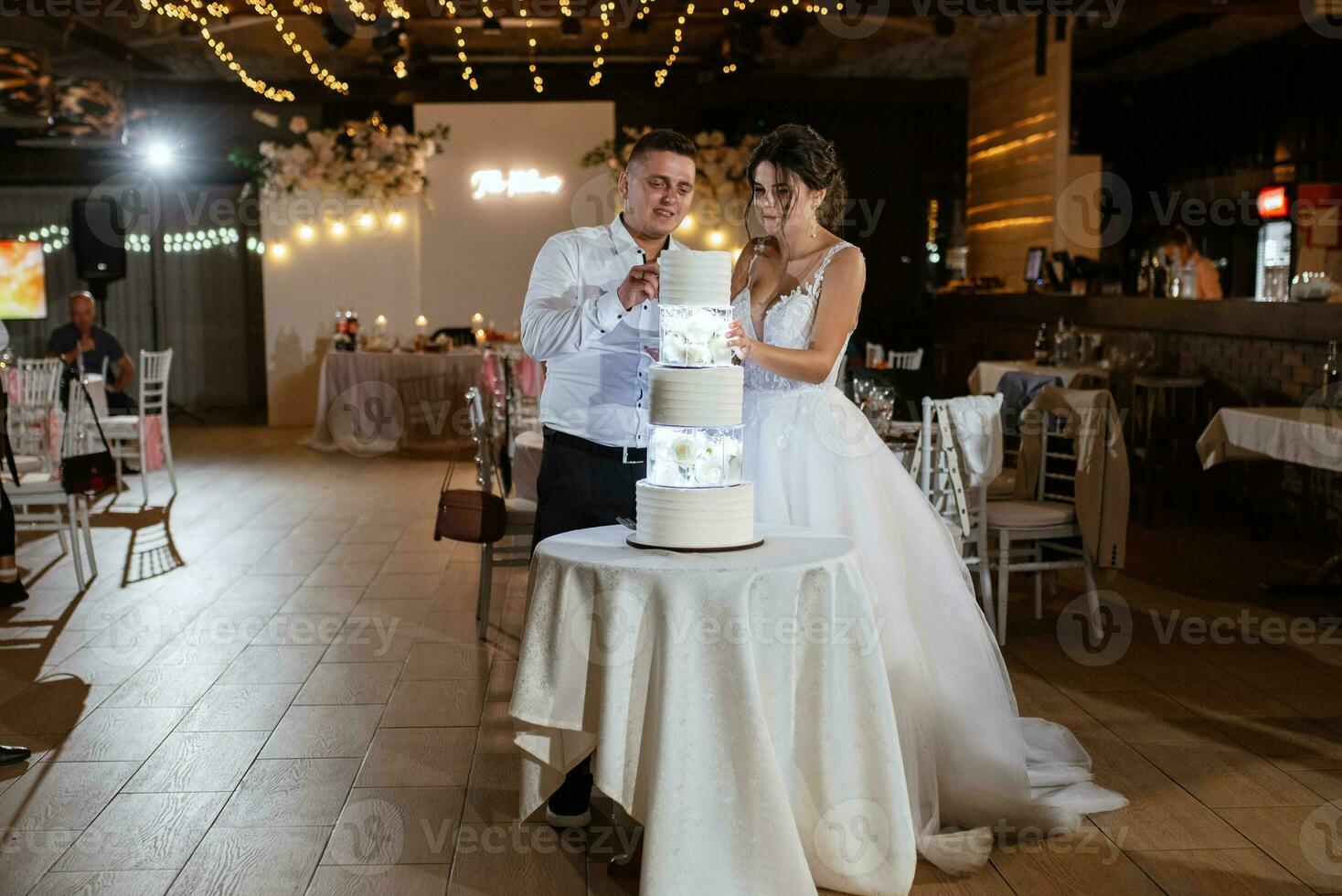 les jeunes mariés coupent et goûtent joyeusement le gâteau de mariage photo