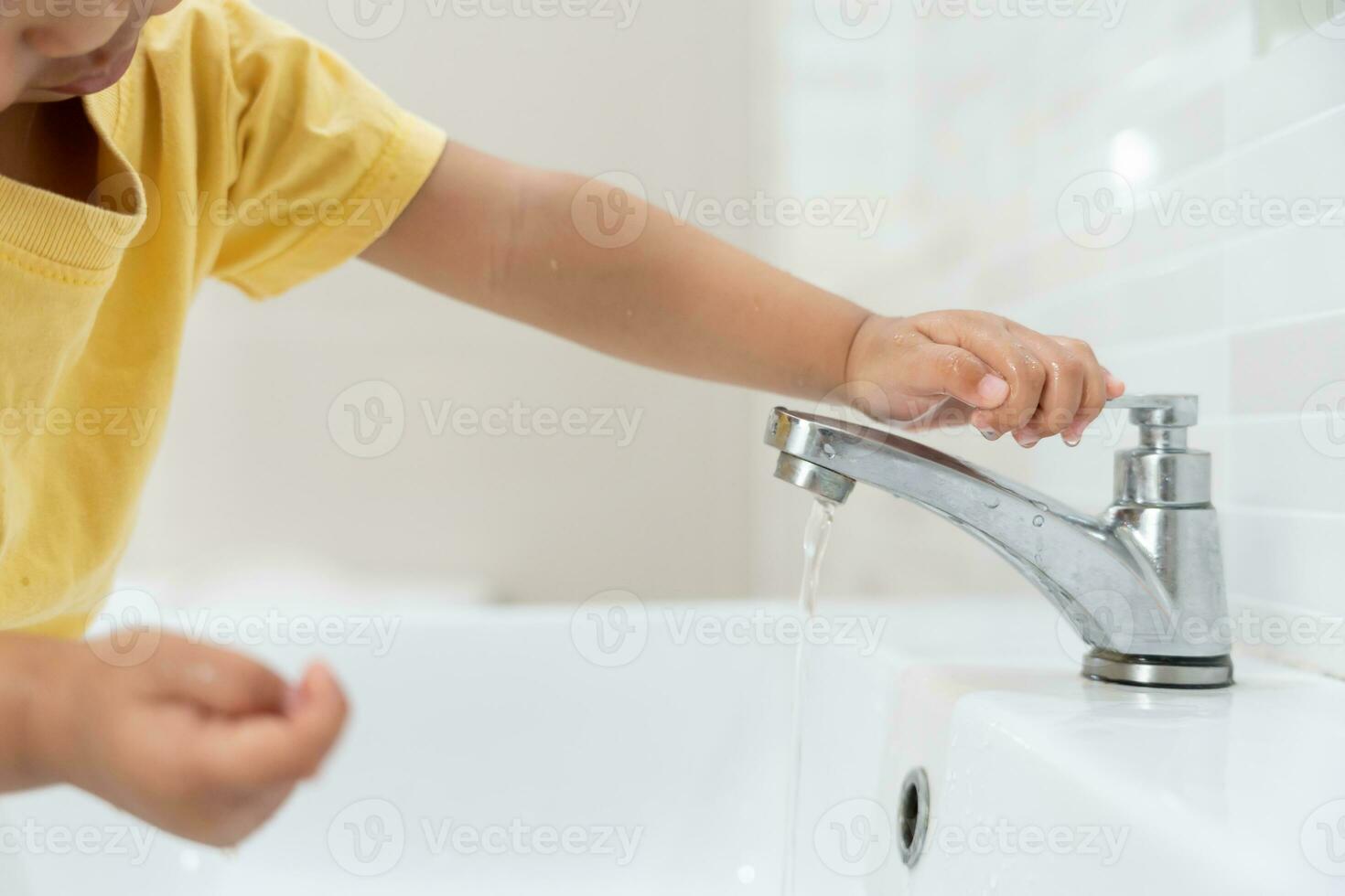 enregistrer l'eau. peu enfant garde tournant de le fonctionnement l'eau dans le salle de bains à protéger environnement. écologisation planète, réduire global échauffement, enregistrer monde, vie, avenir, risque énergie, crise , l'eau journée. photo