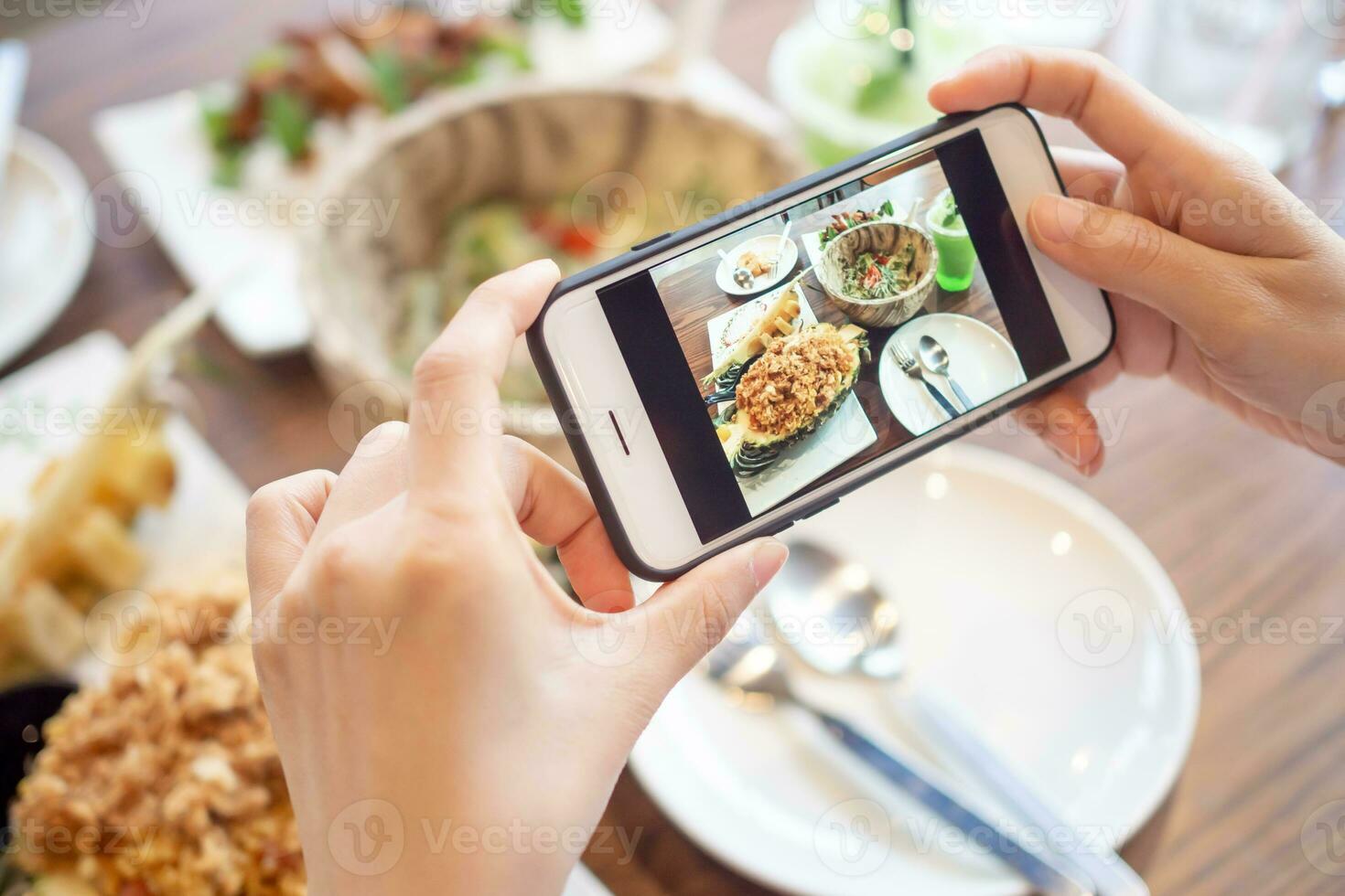 restaurant propriétaire prend une image de le nourriture sur le table avec une téléphone intelligent à Publier sur une site Internet. en ligne nourriture livraison, commande service, influenceur, examen, social médias, partager, commercialisation, intérêt. photo