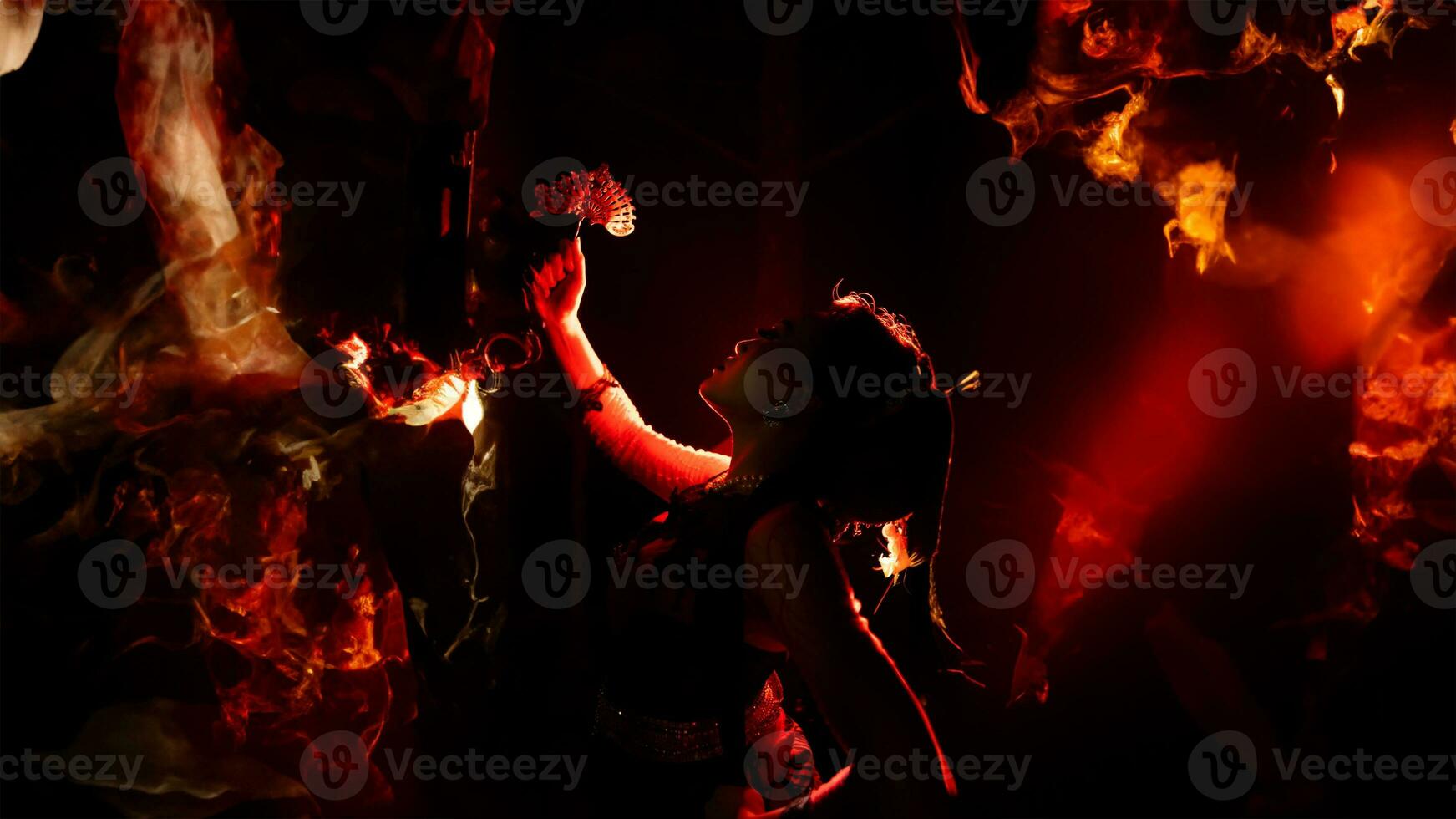 le silhouette de une femelle Danseur en portant pétillant bijoux et à la recherche tranchant dans le foncé avec Feu brûlant dans le Contexte photo