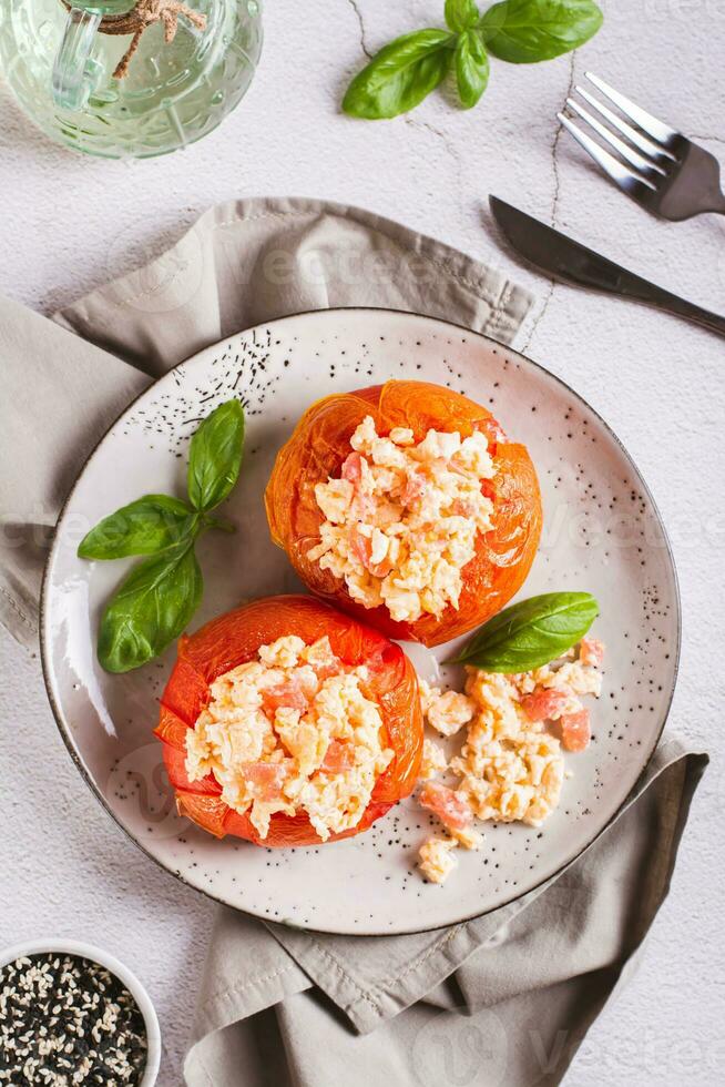 des œufs cuit dans mûr tomates et basilic sur une assiette sur le table Haut et verticale vue photo