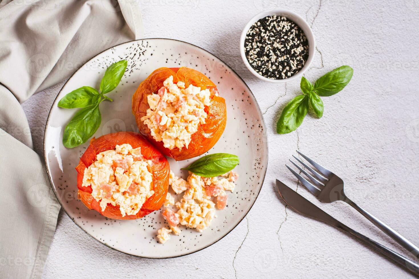 cuit tomate moitiés rempli avec brouillé Oeuf et basilic sur une assiette sur le table Haut vue photo