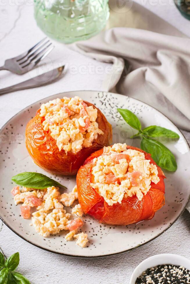 des œufs cuit dans mûr tomates et basilic sur une assiette sur le table verticale vue photo