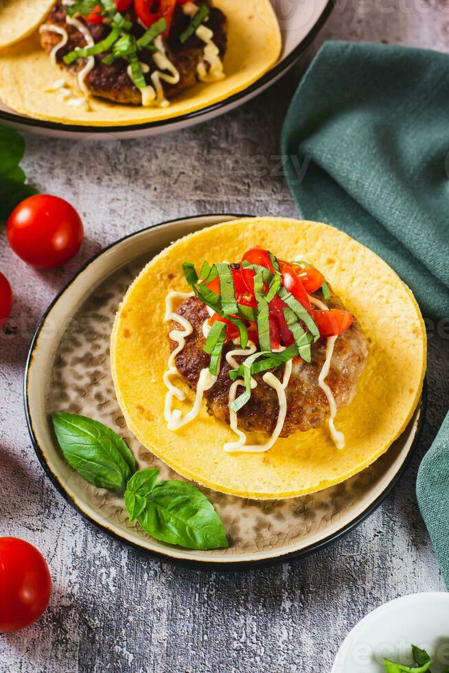 fracasser Burger tacos avec du boeuf petit pâté, tomates et basilic sur une assiette verticale vue photo