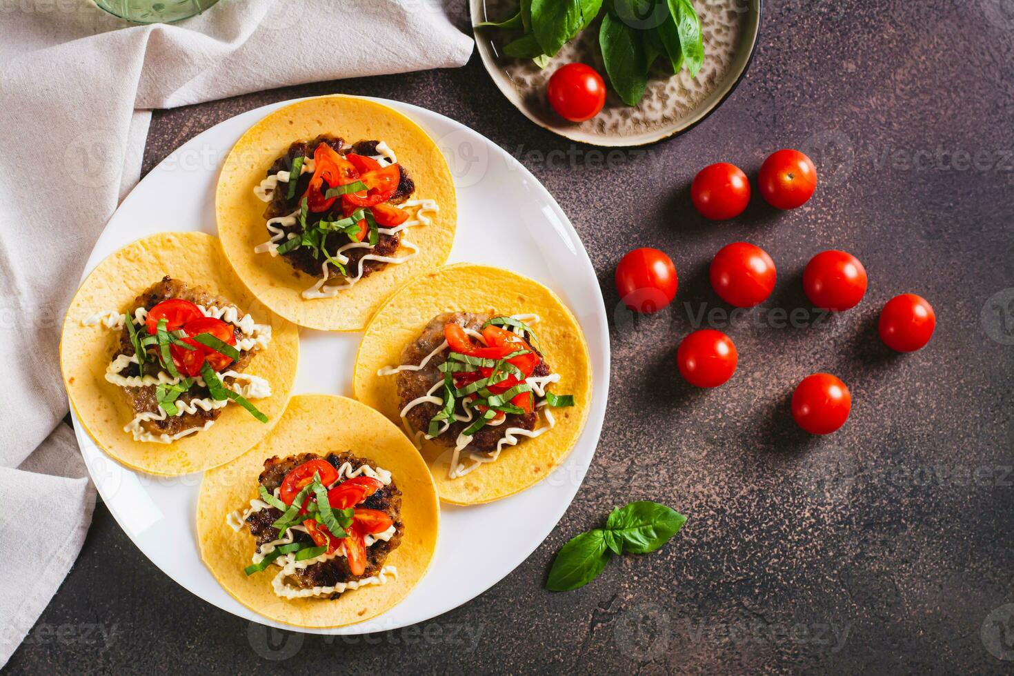 fracasser Burger tacos avec tomates, sauce et herbes sur une assiette sur le table Haut vue photo