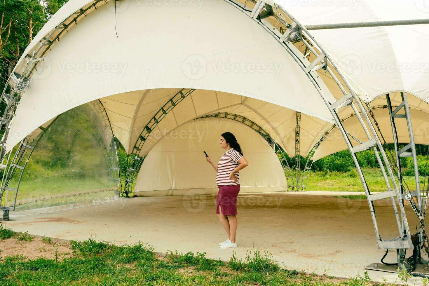 femelle organisateur les usages une téléphone intelligent tandis que permanent dans un vide tente pavillon pour rue Masse événements photo