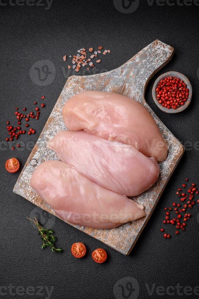 filet de poulet frais sur une table en béton foncé avec des épices et des herbes photo