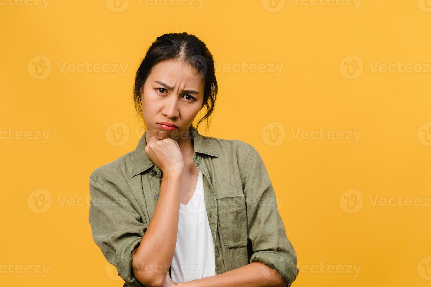 jeune femme asiatique avec une expression négative, hurlant d'excitation, pleurant émotionnellement en colère dans des vêtements décontractés et regarde la caméra isolée sur fond jaune avec un espace de copie vierge. concept d'expression faciale photo