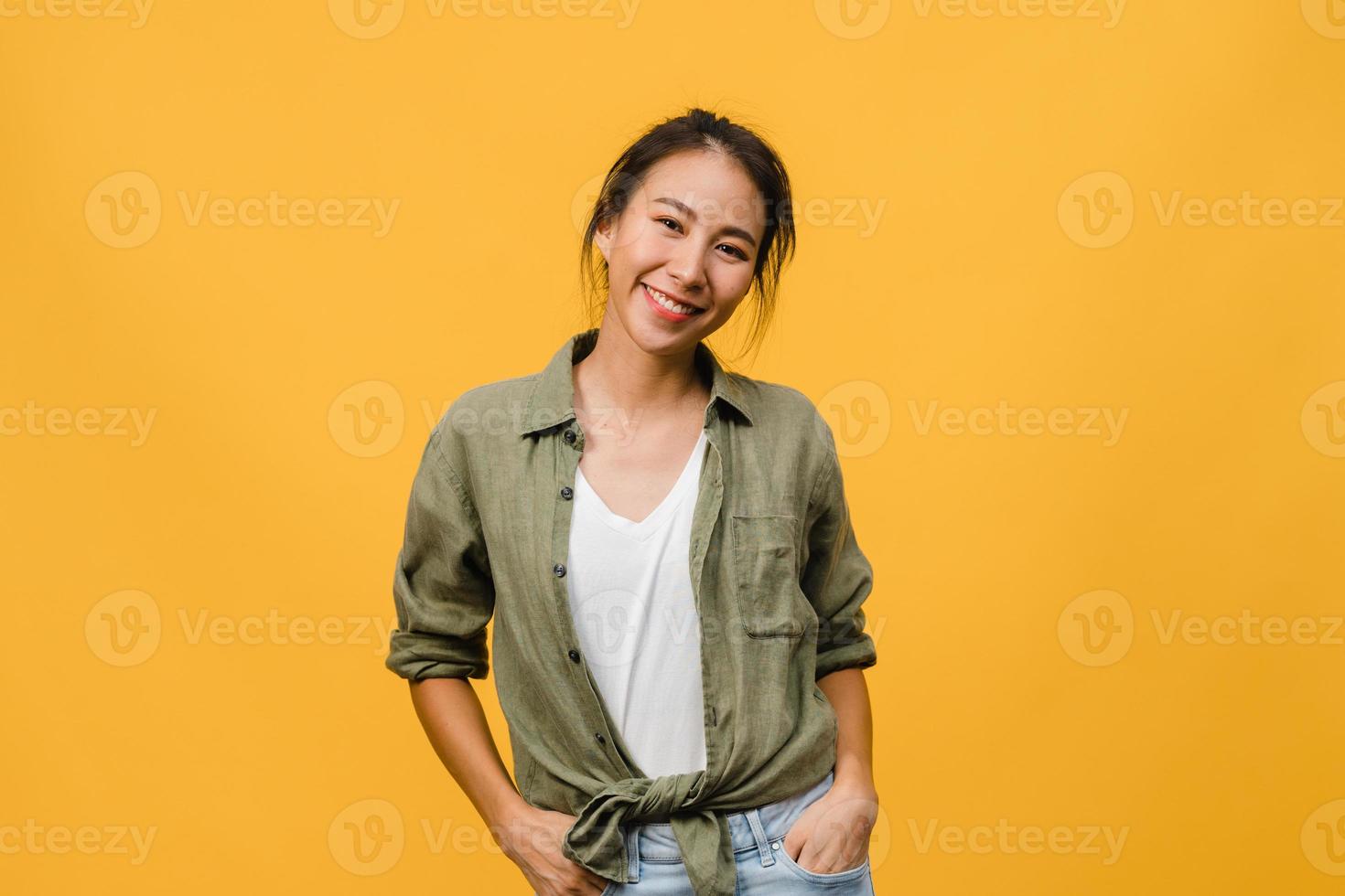 jeune femme asiatique à l'expression positive, sourire largement, vêtue de vêtements décontractés et regardant la caméra sur fond jaune. heureuse adorable femme heureuse se réjouit du succès. concept d'expression faciale. photo