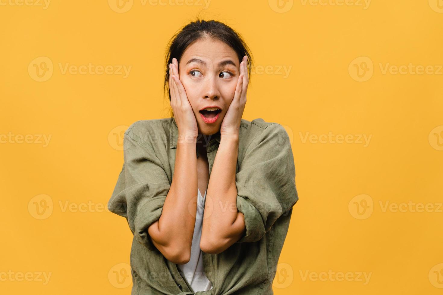 la jeune femme asiatique ressent le bonheur avec une expression positive, une joyeuse surprise funky, vêtue d'un tissu décontracté isolé sur fond jaune. heureuse adorable femme heureuse se réjouit du succès. expression faciale. photo