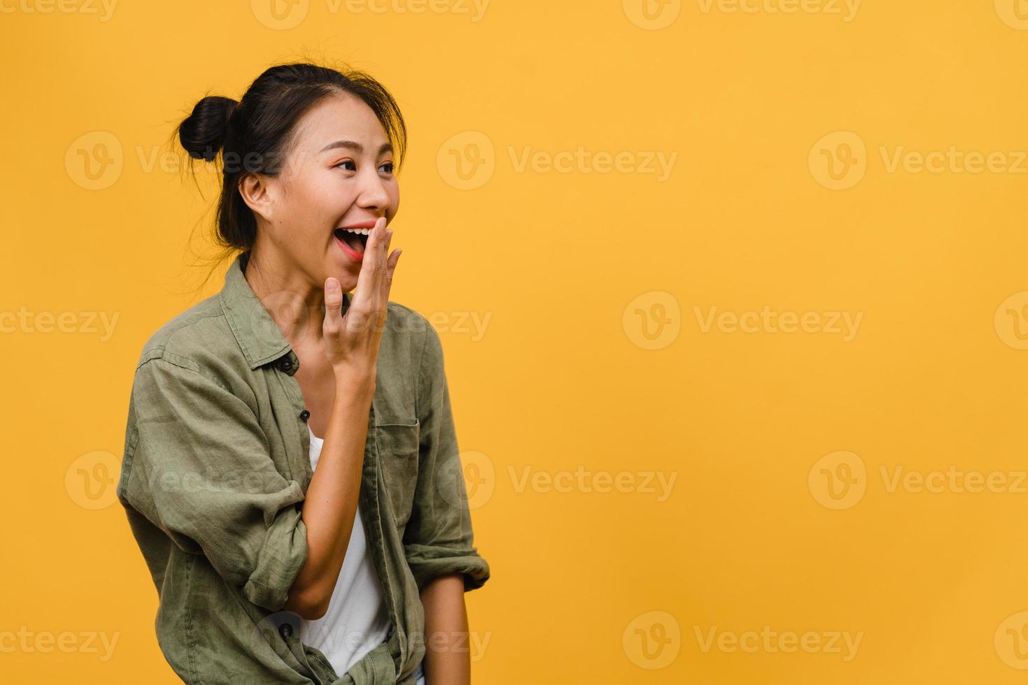 la jeune femme asiatique ressent le bonheur avec une expression positive, une joyeuse surprise funky, vêtue d'un tissu décontracté isolé sur fond jaune. heureuse adorable femme heureuse se réjouit du succès. expression faciale. photo