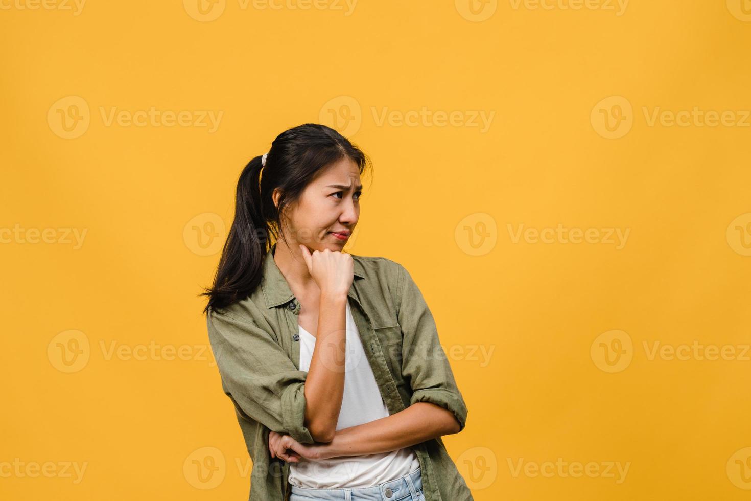 portrait d'une jeune femme asiatique avec une expression négative, des cris excités, des pleurs émotionnels en colère dans des vêtements décontractés isolés sur fond jaune avec un espace de copie vierge. concept d'expression faciale. photo