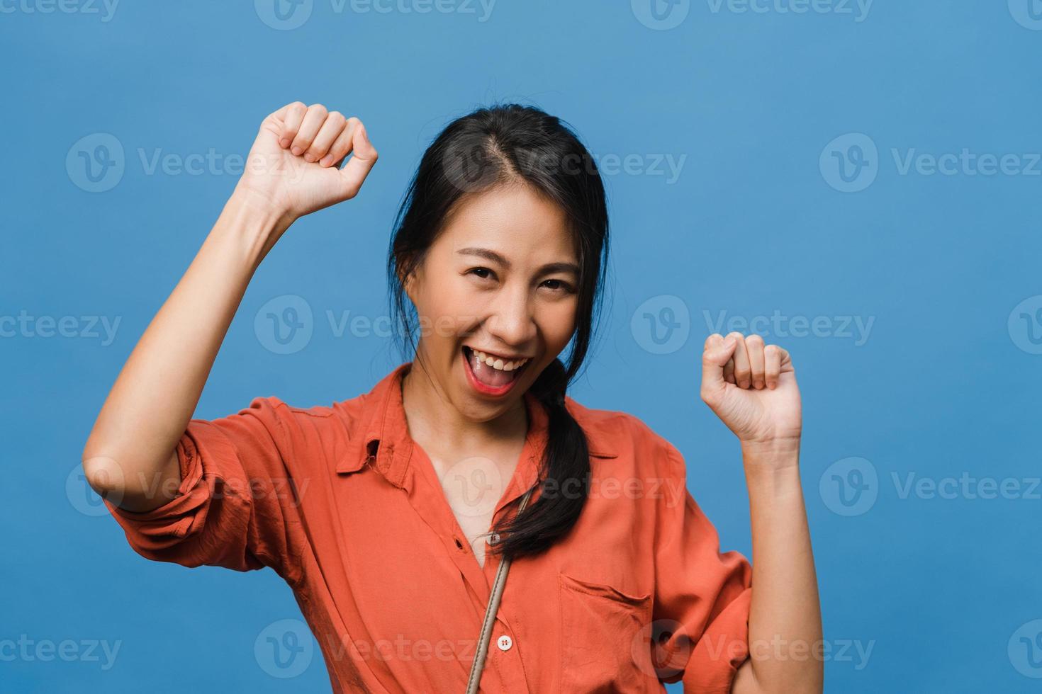 jeune femme asiatique à l'expression positive, joyeuse et excitante, vêtue d'un tissu décontracté et regarde la caméra sur fond bleu. heureuse adorable femme heureuse se réjouit du succès. concept d'expression faciale. photo