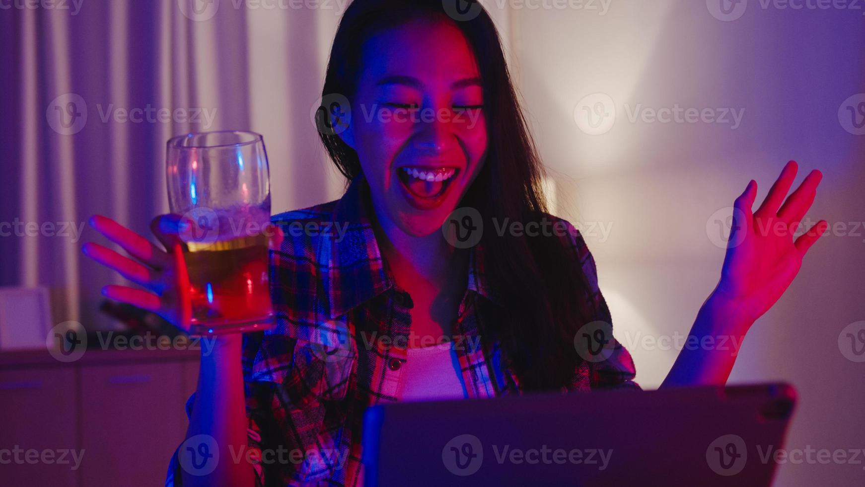 jeune femme asiatique buvant de la bière s'amusant moment heureux disco néon soirée événement célébration en ligne via appel vidéo dans le salon à la maison. distanciation sociale, quarantaine pour la prévention des coronavirus. photo