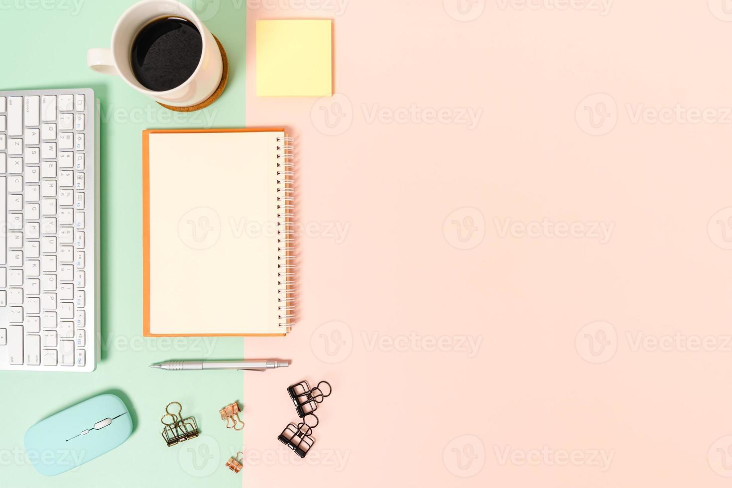 photo créative à plat du bureau de l'espace de travail. bureau vue de dessus avec clavier, souris et cahier noir maquette ouverte sur fond de couleur rose vert pastel. vue de dessus maquette avec copie espace photographie.