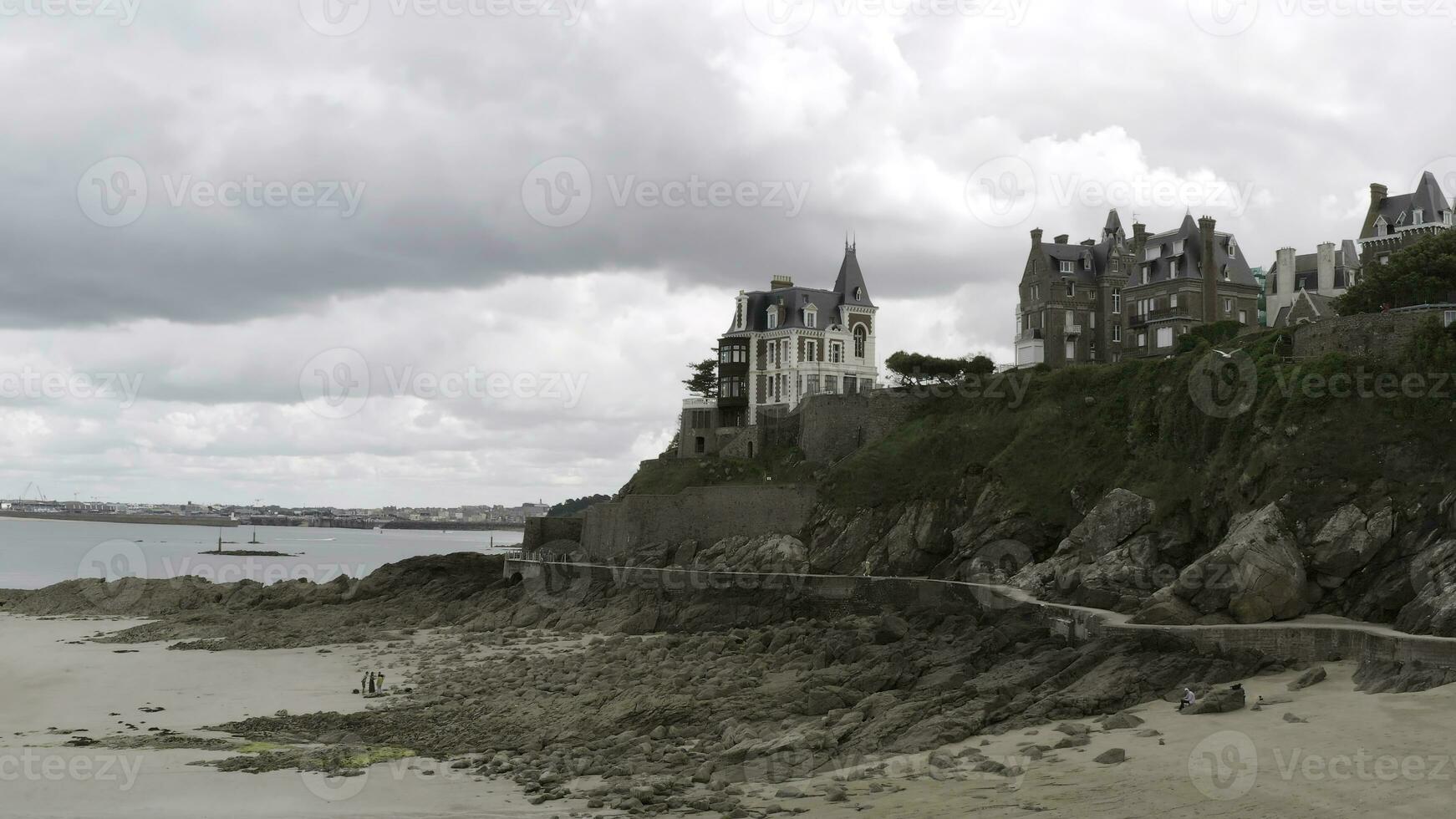 panoramique aérien vue de le chalets de blanc et rouge briques situé sur le rebord par le mer rive. action. côté vue de le brique Maisons près le côte ligne sur nuageux ciel Contexte. photo