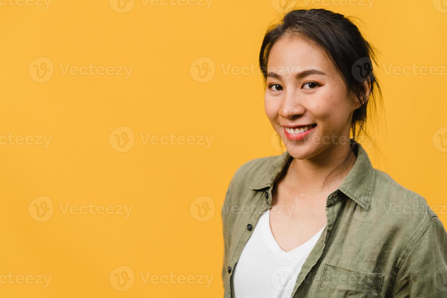 jeune femme asiatique à l'expression positive, sourire largement, vêtue de vêtements décontractés et regardant la caméra sur fond jaune. heureuse adorable femme heureuse se réjouit du succès. concept d'expression faciale. photo