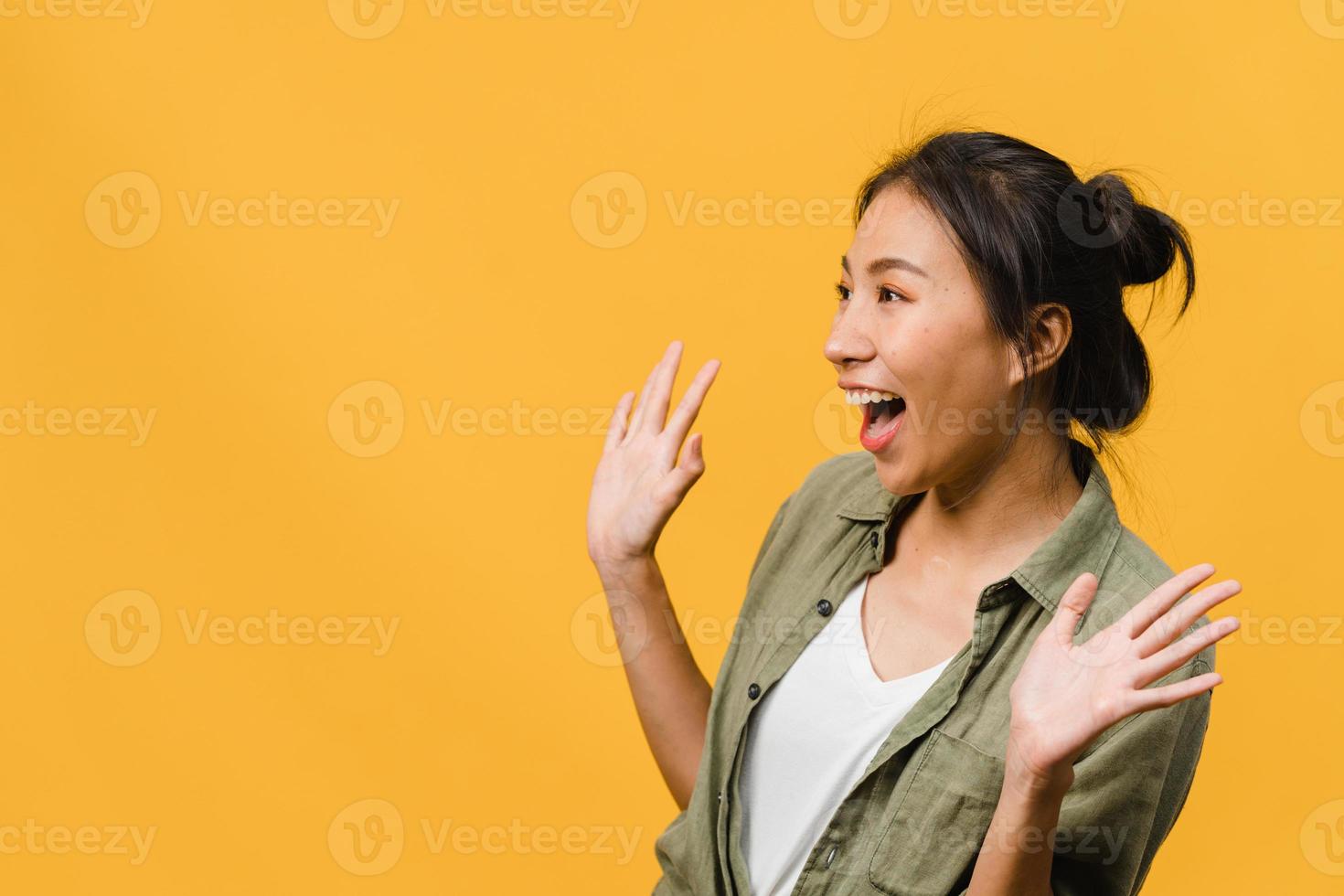 la jeune femme asiatique ressent le bonheur avec une expression positive, une joyeuse surprise funky, vêtue d'un tissu décontracté isolé sur fond jaune. heureuse adorable femme heureuse se réjouit du succès. expression faciale. photo