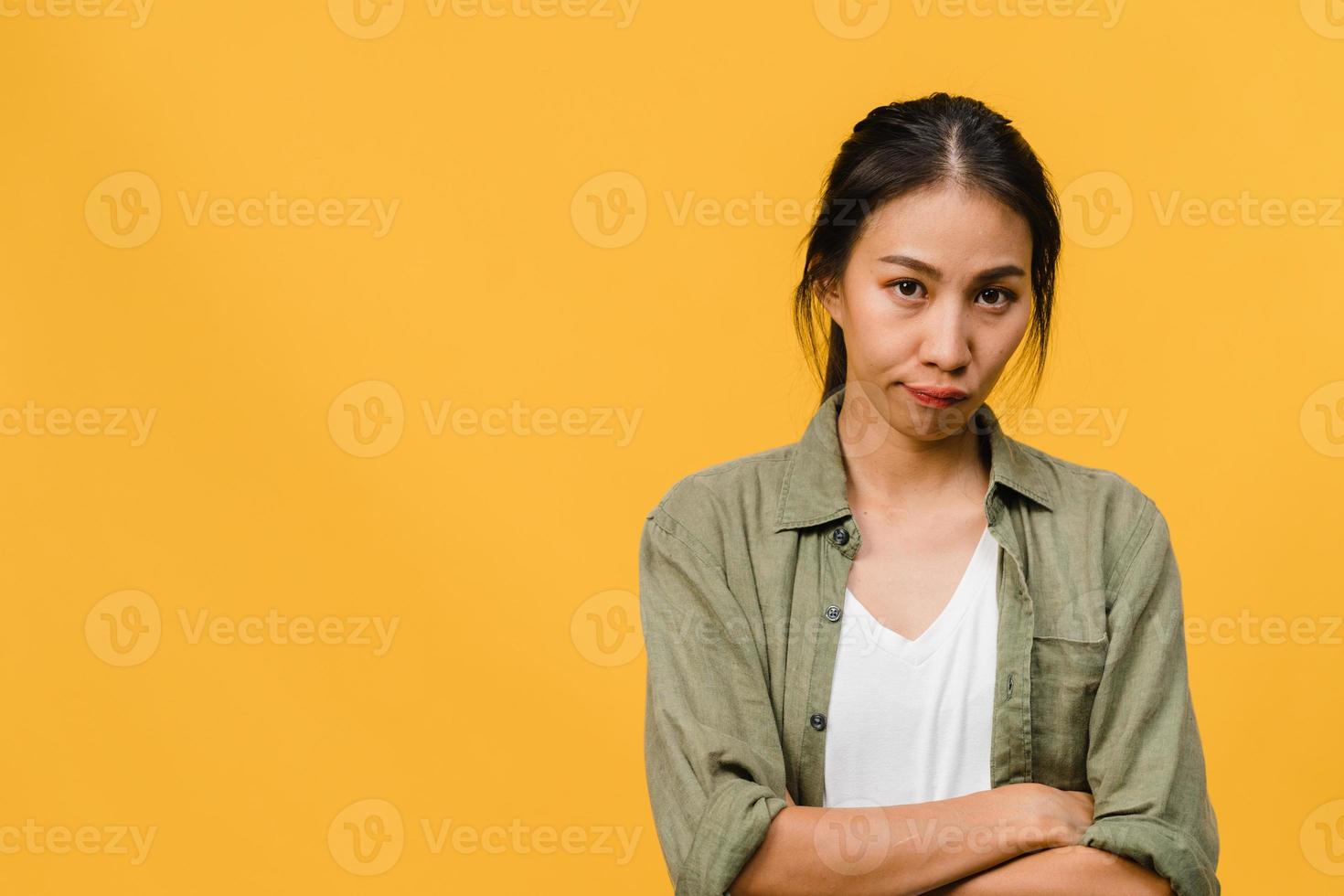 jeune femme asiatique avec une expression négative, hurlant d'excitation, pleurant émotionnellement en colère dans des vêtements décontractés et regarde la caméra isolée sur fond jaune avec un espace de copie vierge. concept d'expression faciale photo