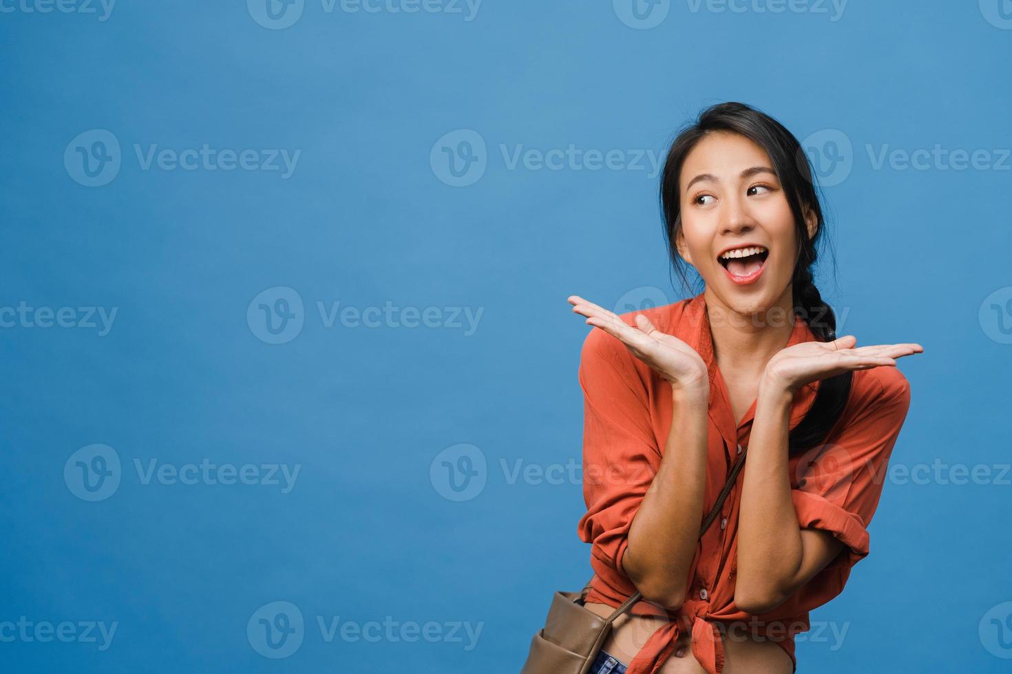 la jeune femme asiatique ressent le bonheur avec une expression positive, une joyeuse surprise funky, vêtue d'un tissu décontracté isolé sur fond bleu. heureuse adorable femme heureuse se réjouit du succès. expression faciale. photo