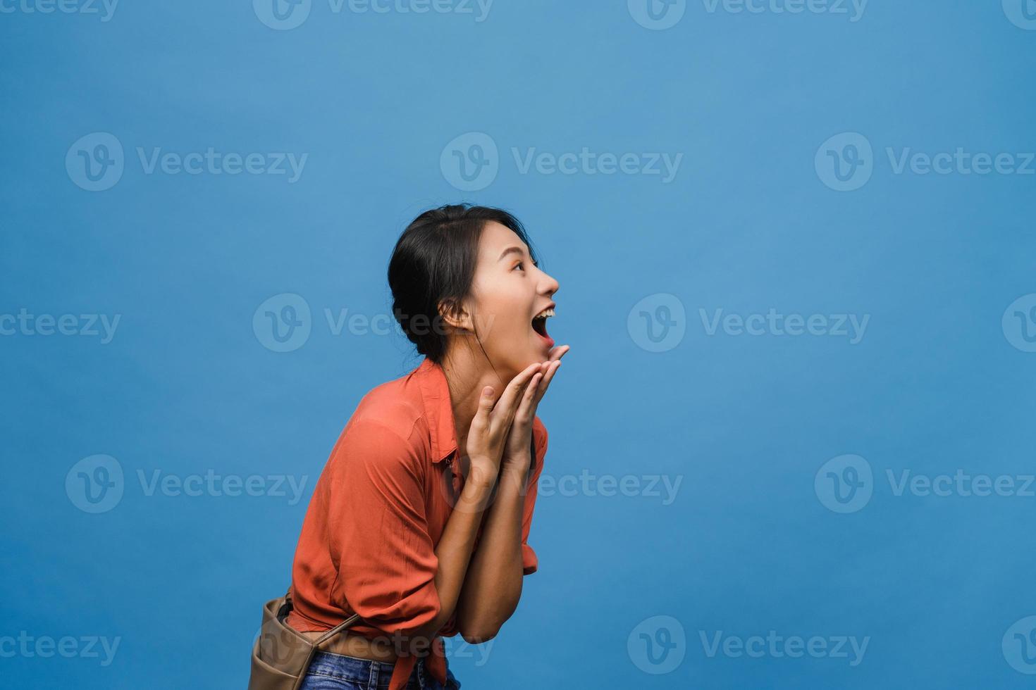 la jeune femme asiatique ressent le bonheur avec une expression positive, une joyeuse surprise funky, vêtue d'un tissu décontracté isolé sur fond bleu. heureuse adorable femme heureuse se réjouit du succès. expression faciale. photo