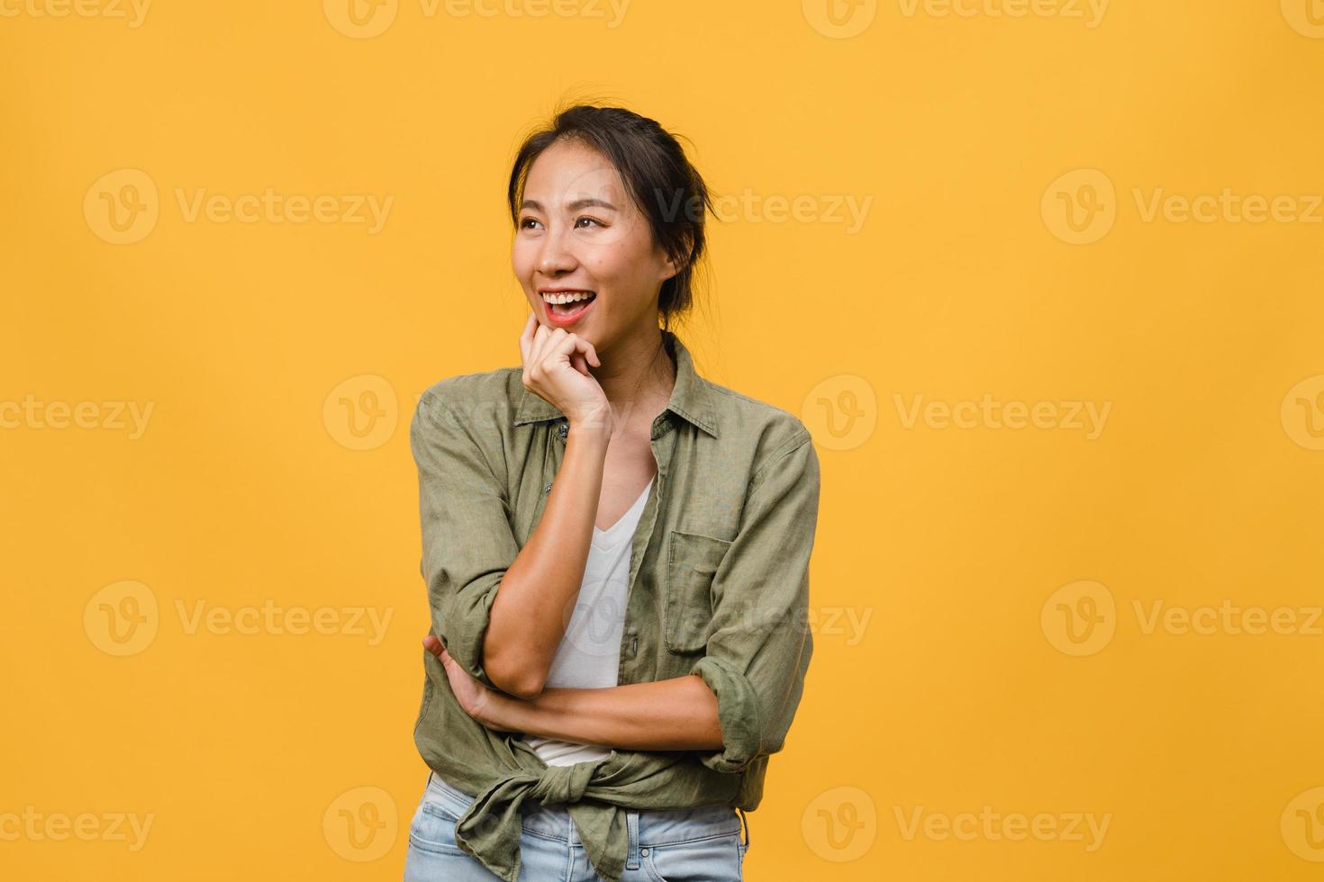portrait d'une jeune femme asiatique à l'expression positive, bras croisés, sourire largement, vêtue d'un tissu décontracté sur fond jaune. heureuse adorable femme heureuse se réjouit du succès. concept d'expression faciale. photo