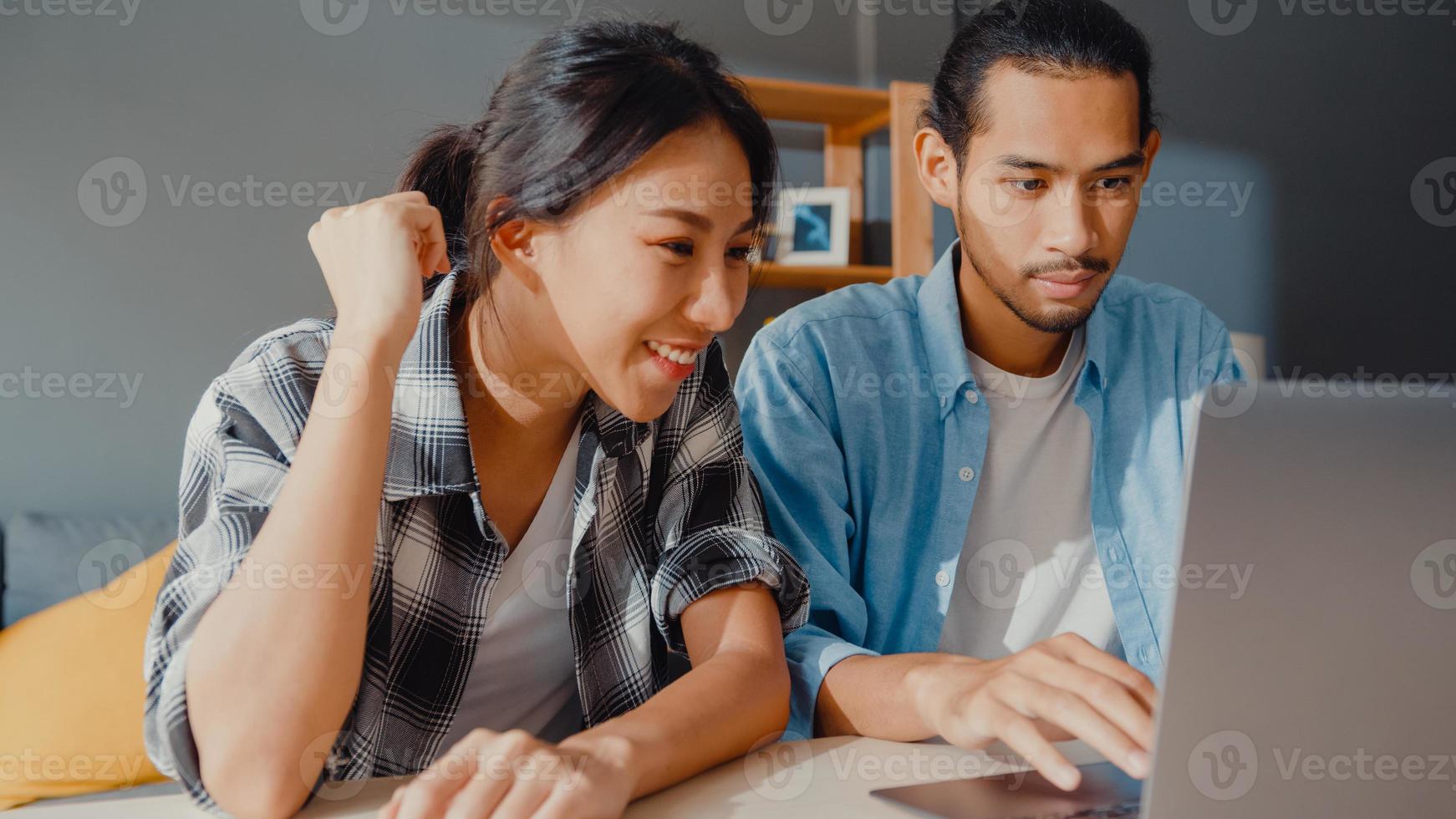 succès asie jeune couple homme et femme ravis enthousiasmés accord de prêt bancaire maready pour une nouvelle maison en ligne dans un ordinateur portable à la maison, mari et femme heureux heureux de l'investissement financier bonne nouvelle. photo