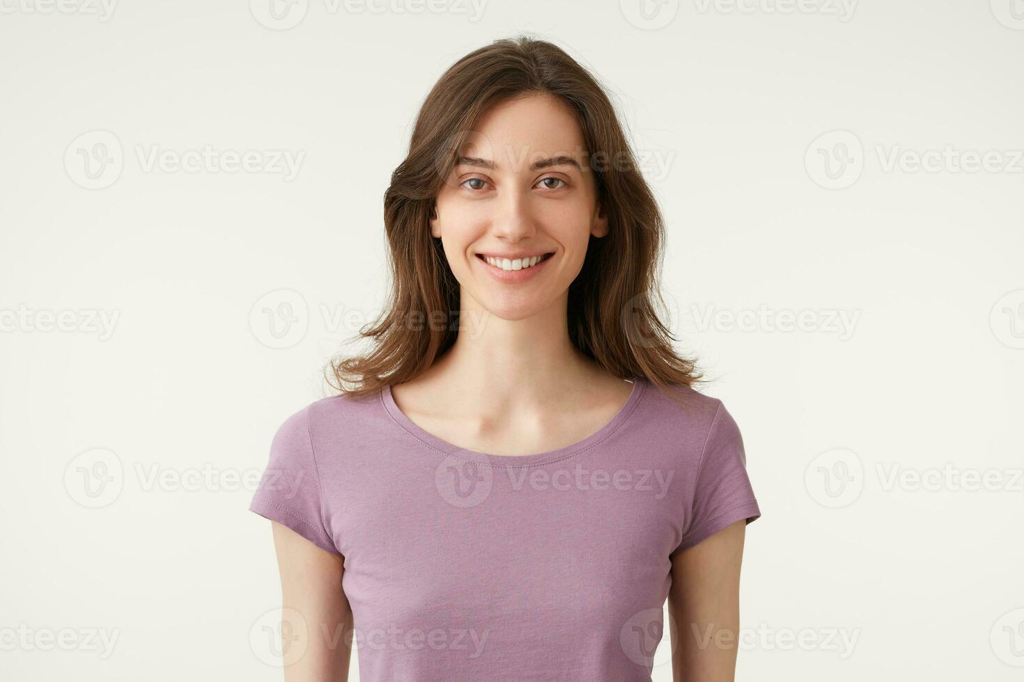 portrait de une magnifique foncé cheveux Jeune fille avec Naturel se maquiller, tendrement sourires, porte violet t-shirt, isolé sur une blanc Contexte dans studio. photo