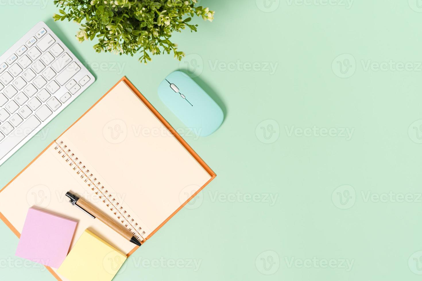 photo créative à plat du bureau de l'espace de travail. bureau vue de dessus avec clavier, souris et bloc-notes noir maquette ouverte sur fond de couleur vert pastel. vue de dessus maquette avec copie espace photographie.