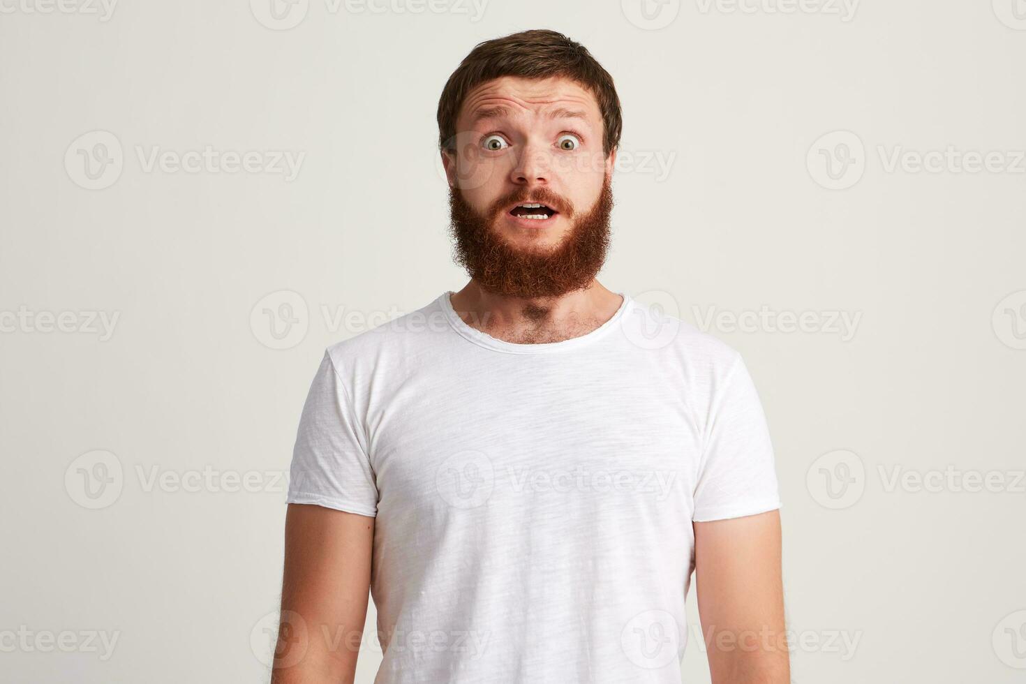 portrait de sous le choc étonné Jeune homme avec barbe et ouvert bouche porte t chemise photo