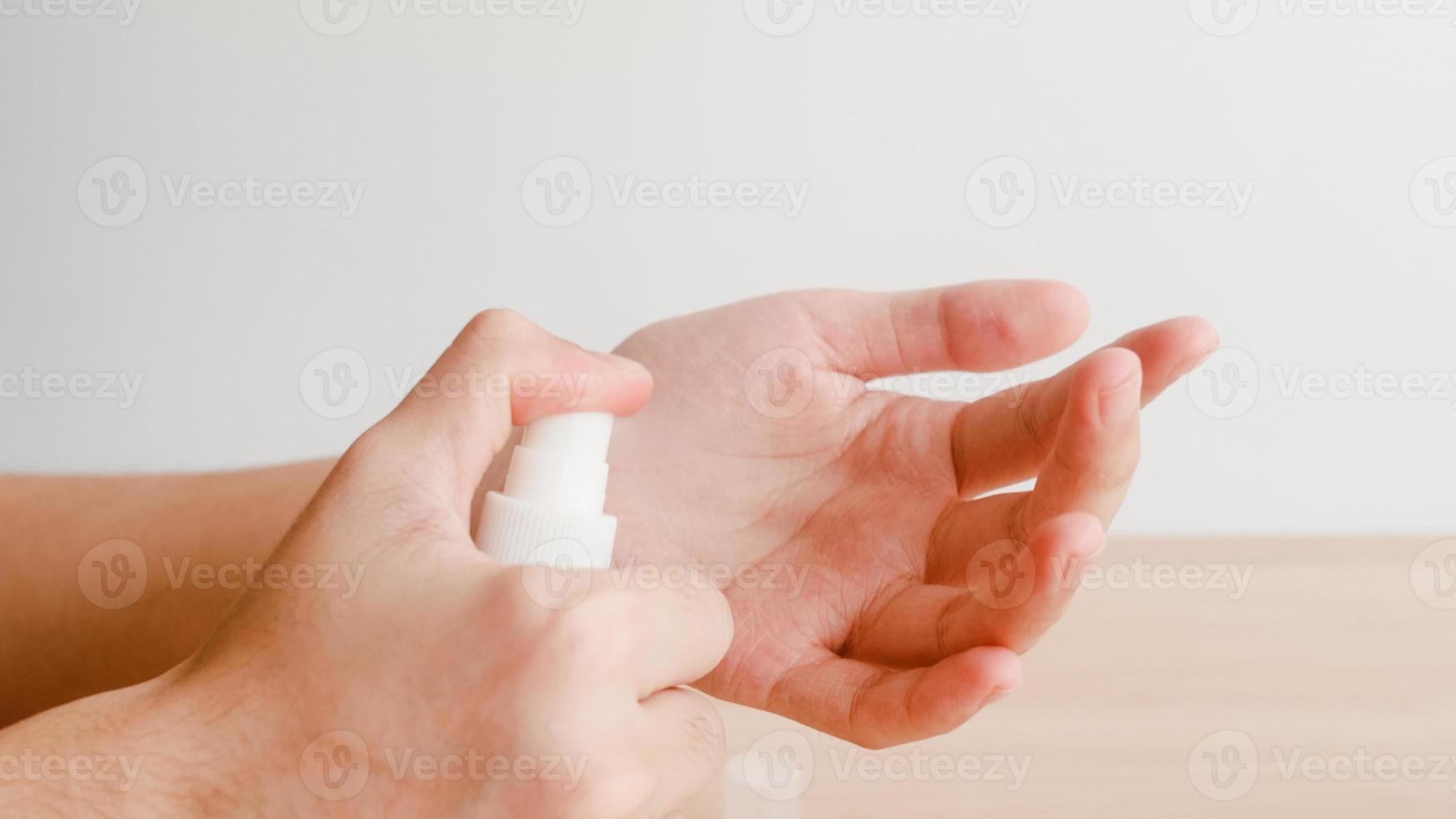 femme asiatique utilisant un désinfectant pour les mains en vaporisateur d'alcool se laver les mains pour protéger le coronavirus. une femme pousse une bouteille d'alcool pour nettoyer la main pour l'hygiène lorsque la distanciation sociale reste à la maison et le temps d'auto-quarantaine. photo